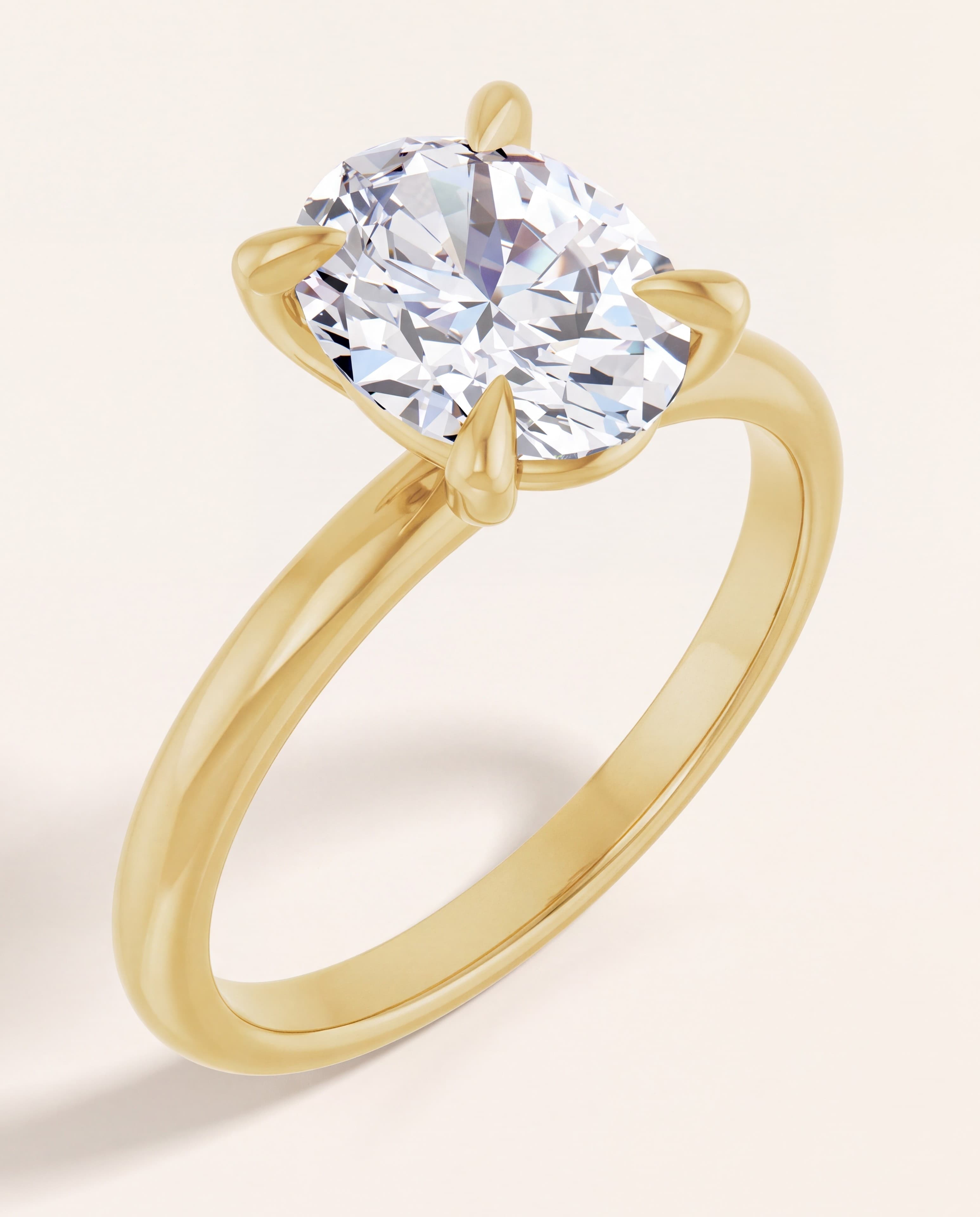 The Ivy oval solitaire in yellow gold on an ivory studio background